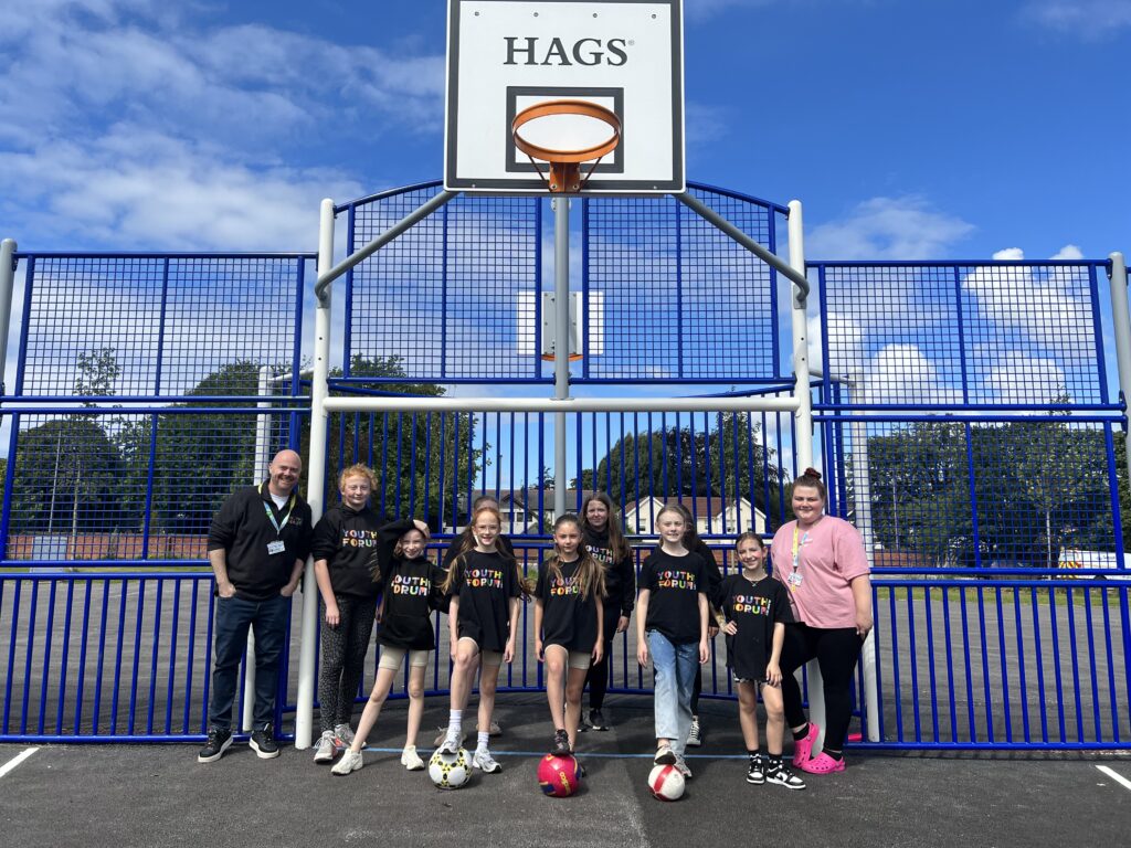 The Youth Forum at Alder Hey pose and smile in front of the goal on the new multi use games area in Springfield Park.