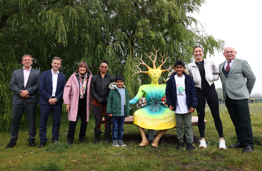 An image of people smiling in front of the climate bench in Springfield Park, Liverpool.