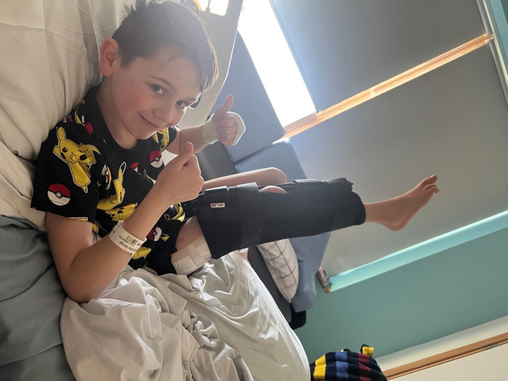 Alfie smiling with his thumbs up after having leg lengthening surgery at Alder Hey