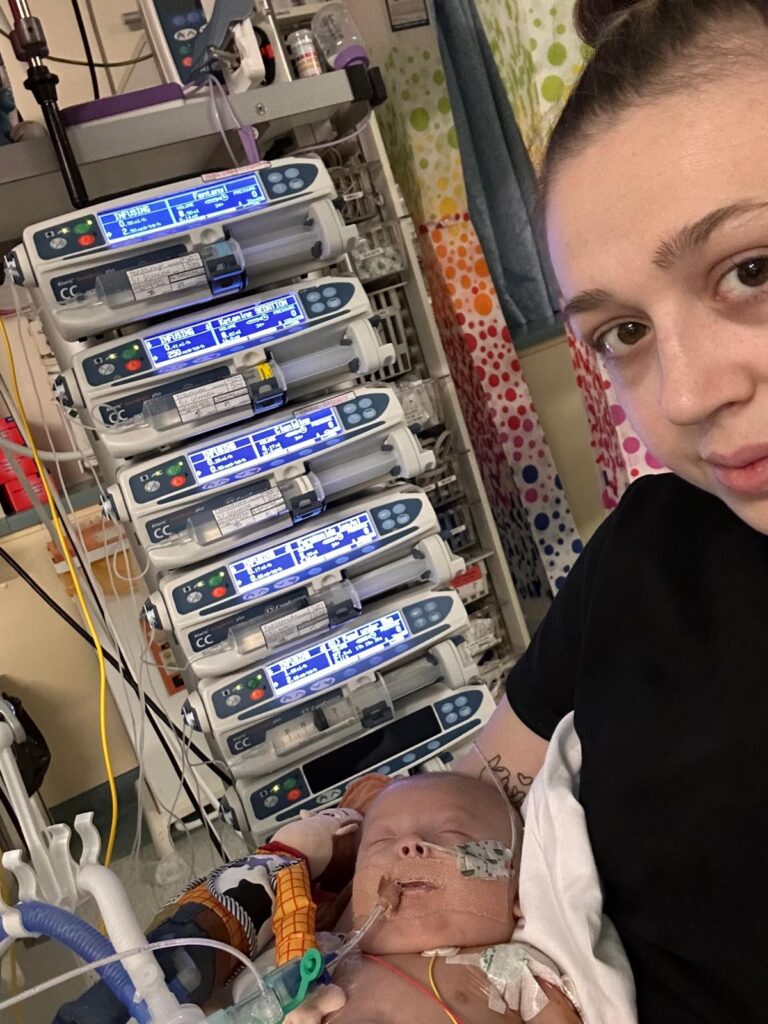 Photo of mum holding a new born baby next to hospital equipment