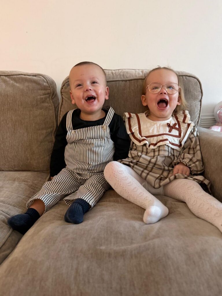 Two babies happy and sitting on a couch