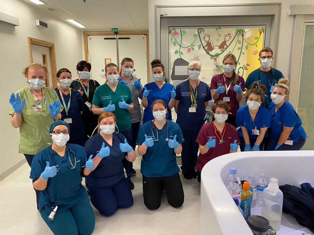 Group photo in A&E with masks on givign a thumbs up