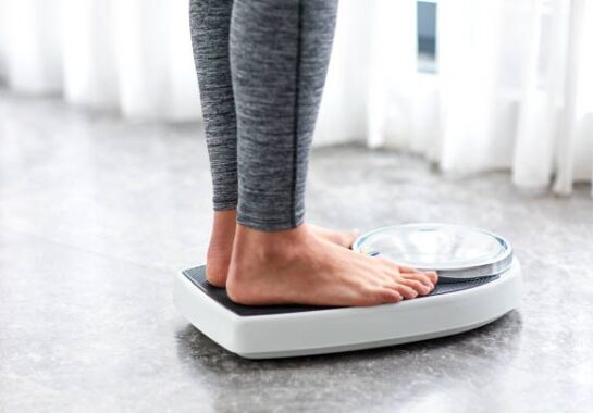 A stock image of a person standing on scales.