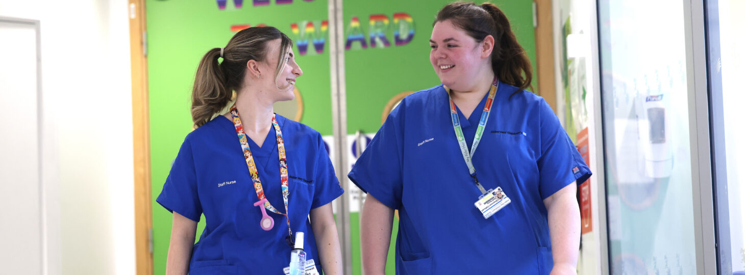 Two staff nurses walking and smiling.