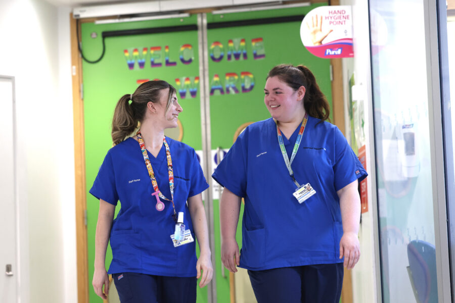 Two staff nurses walking and smiling.