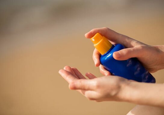 A picture of person's hand spraying sun tan lotion.