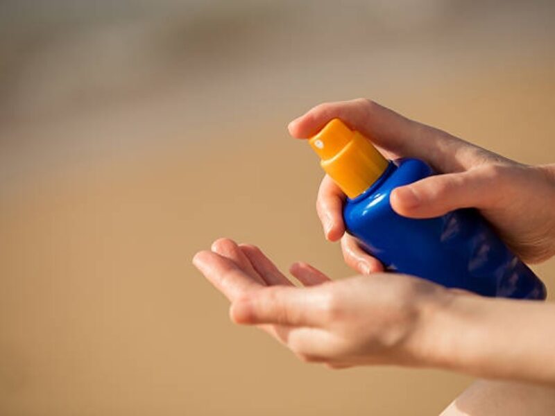 A picture of person's hand spraying sun tan lotion.