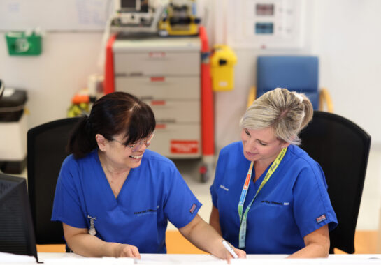 Photo of two nurses sitting down looking at a piece of paper