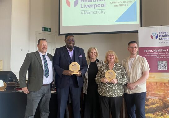 Group photo of people with an award. The background says Fairer Healthier Future