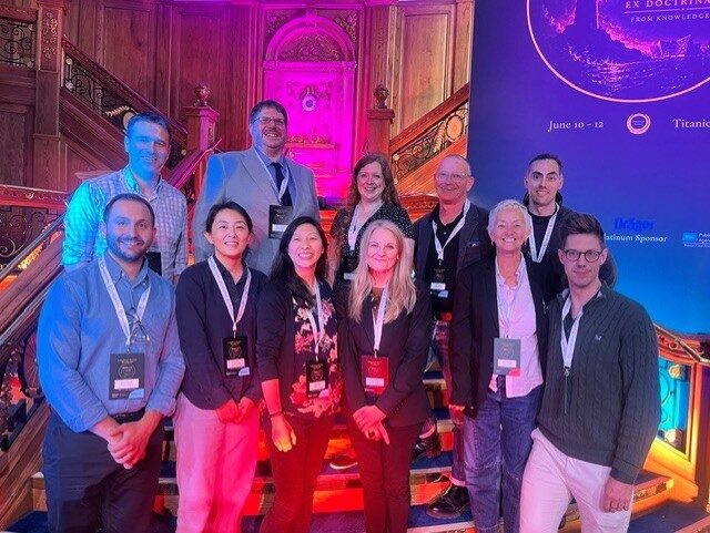 A group of colleagues posing together on a staircase under colourful event lighting.