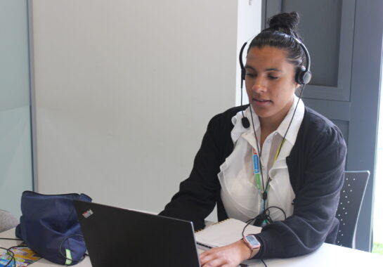 Woman on a headset looking at a laptop
