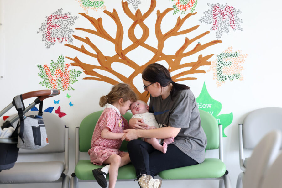 Parent holding baby with sibling next to them