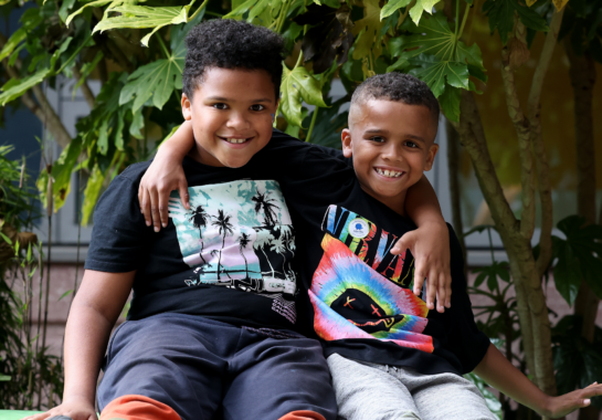 Two children with their arms around each other outside
