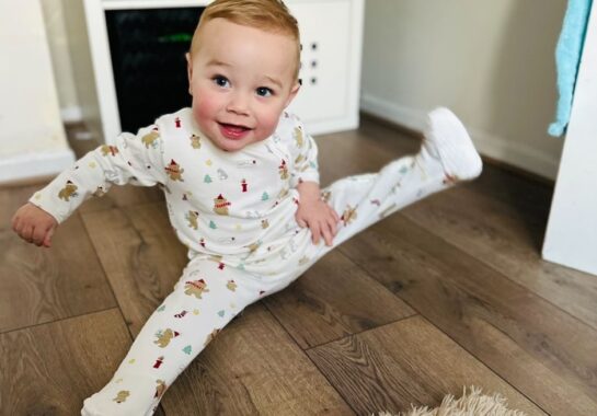 Picture of baby Louis smiling sitting on a wooden floor.