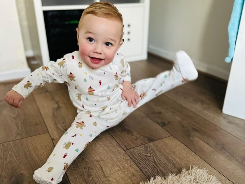 Picture of baby Louis smiling sitting on a wooden floor.