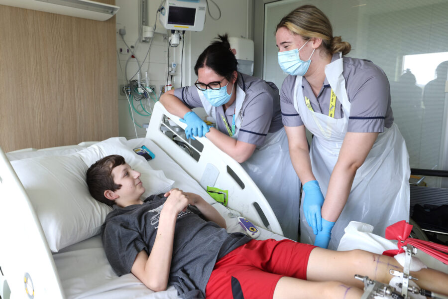 Two student nurses with young person on a ward
